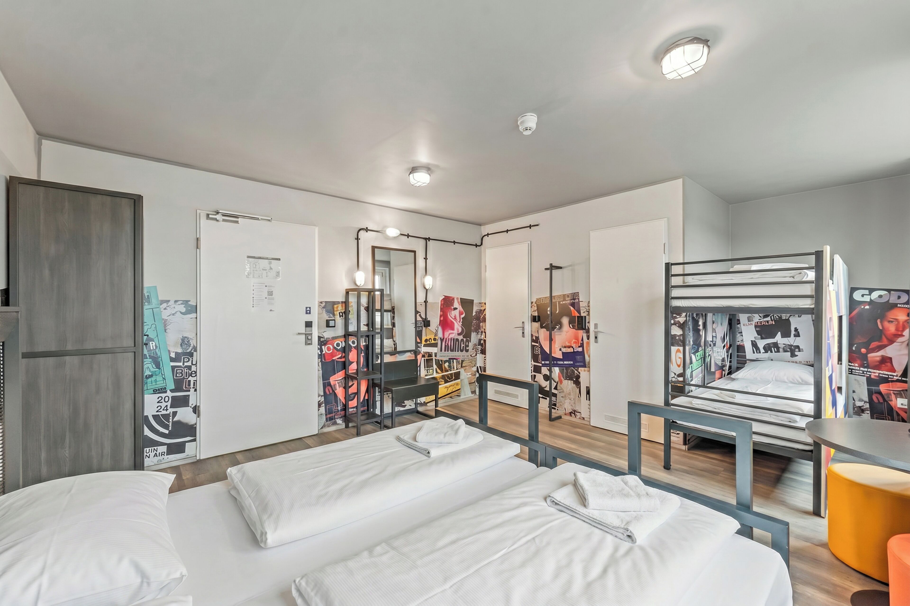 A hotel room with two beds, a desk, a chair, and a mirror.