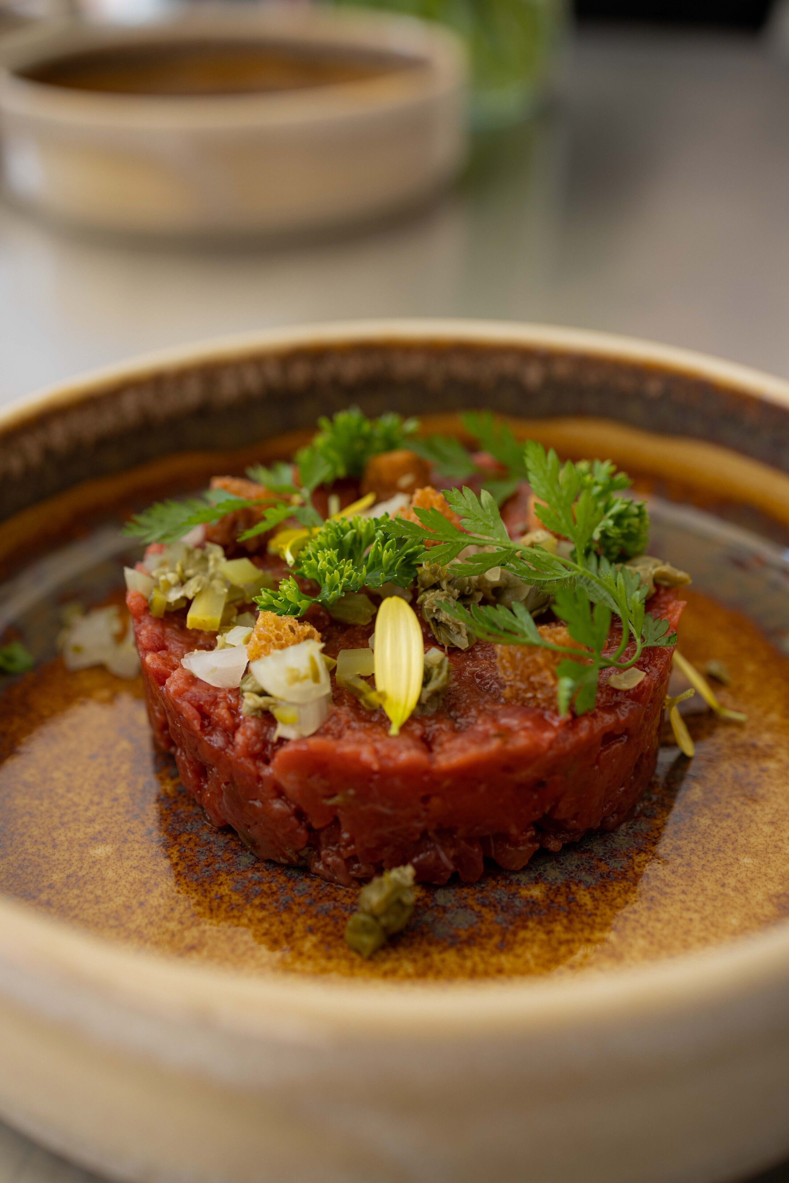 A dish of steak tartare with parsley and onions.
