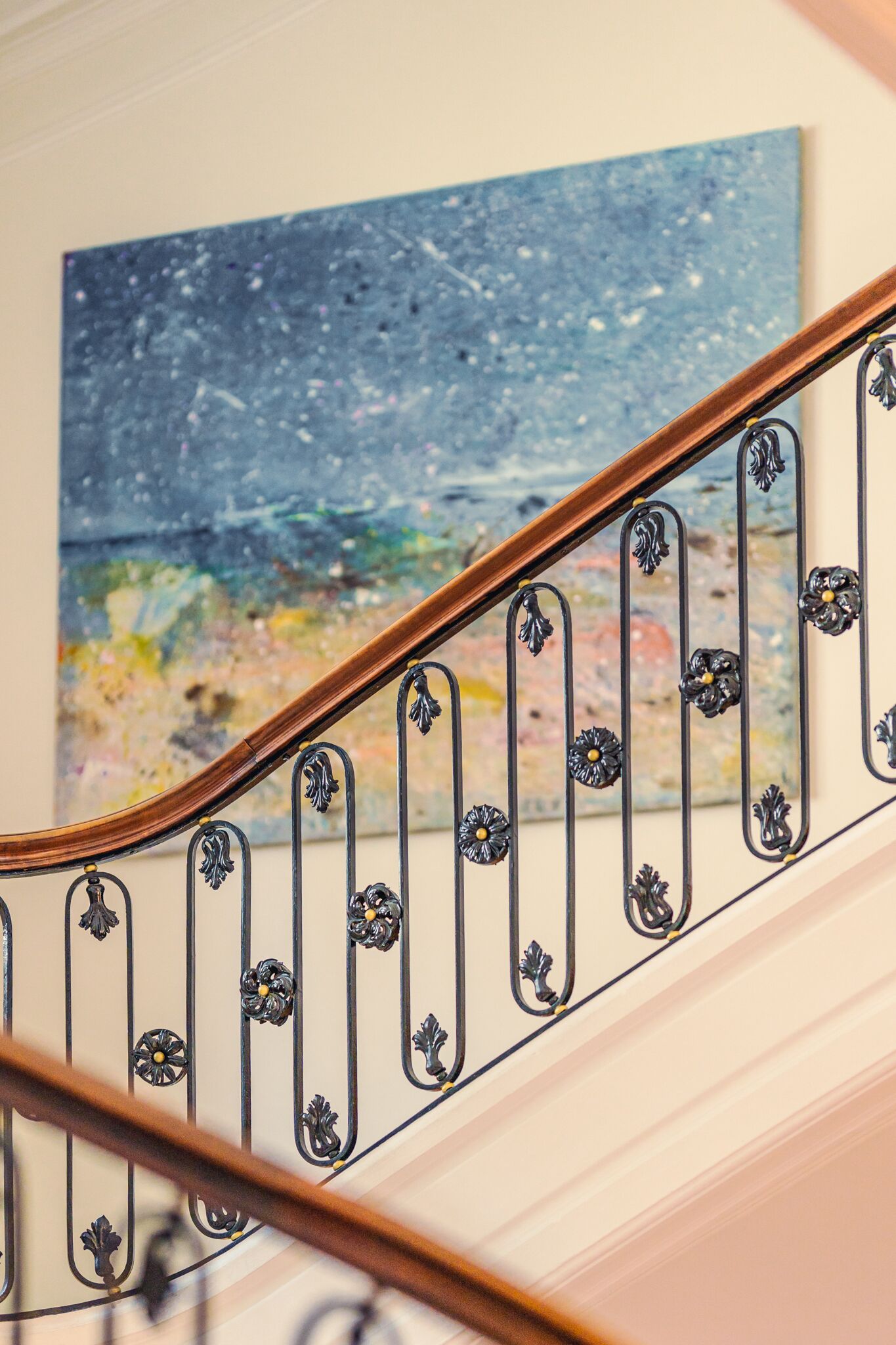 Una scala con ringhiera in legno e balaustre in metallo nero con decorazioni floreali.