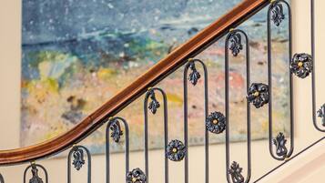 A staircase with a wooden handrail and black metal balusters with floral designs.