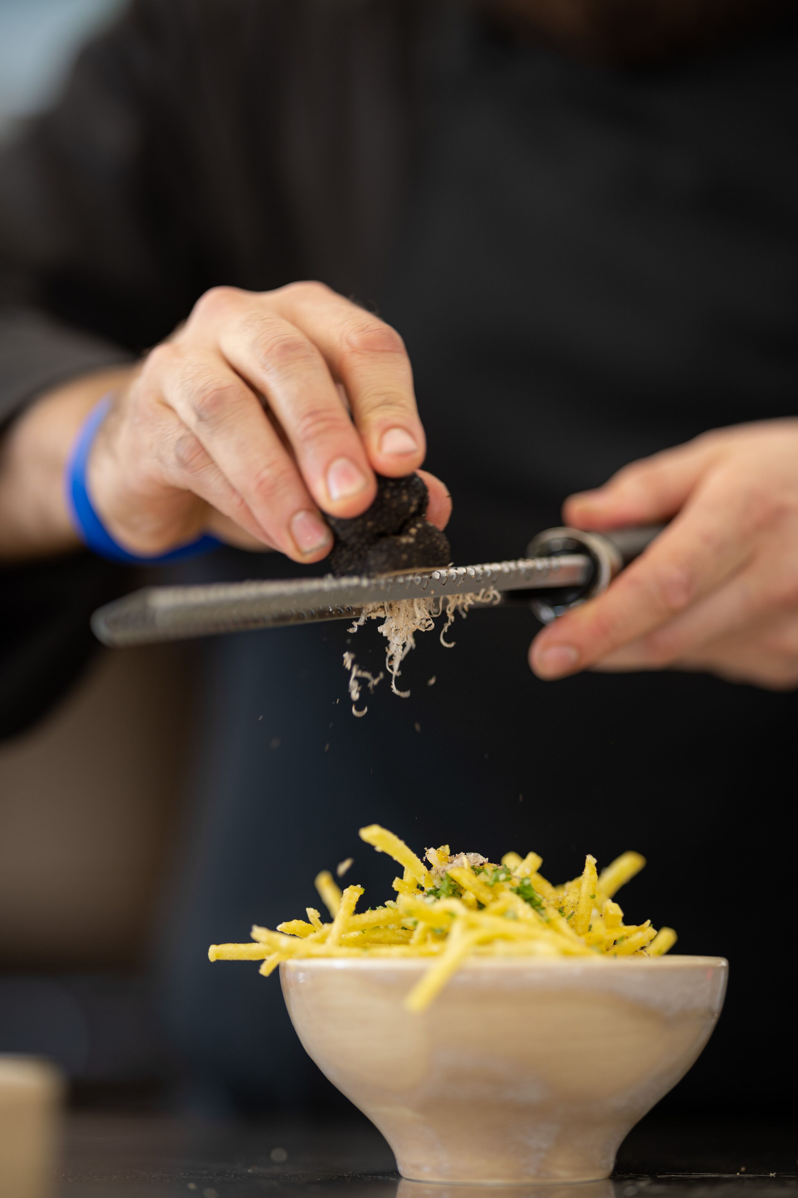 A person grating cheese over a bowl of food.