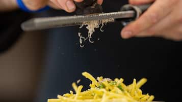 A person grating cheese over a bowl of food.