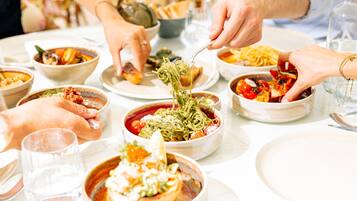 A dining table with various dishes and people eating.
