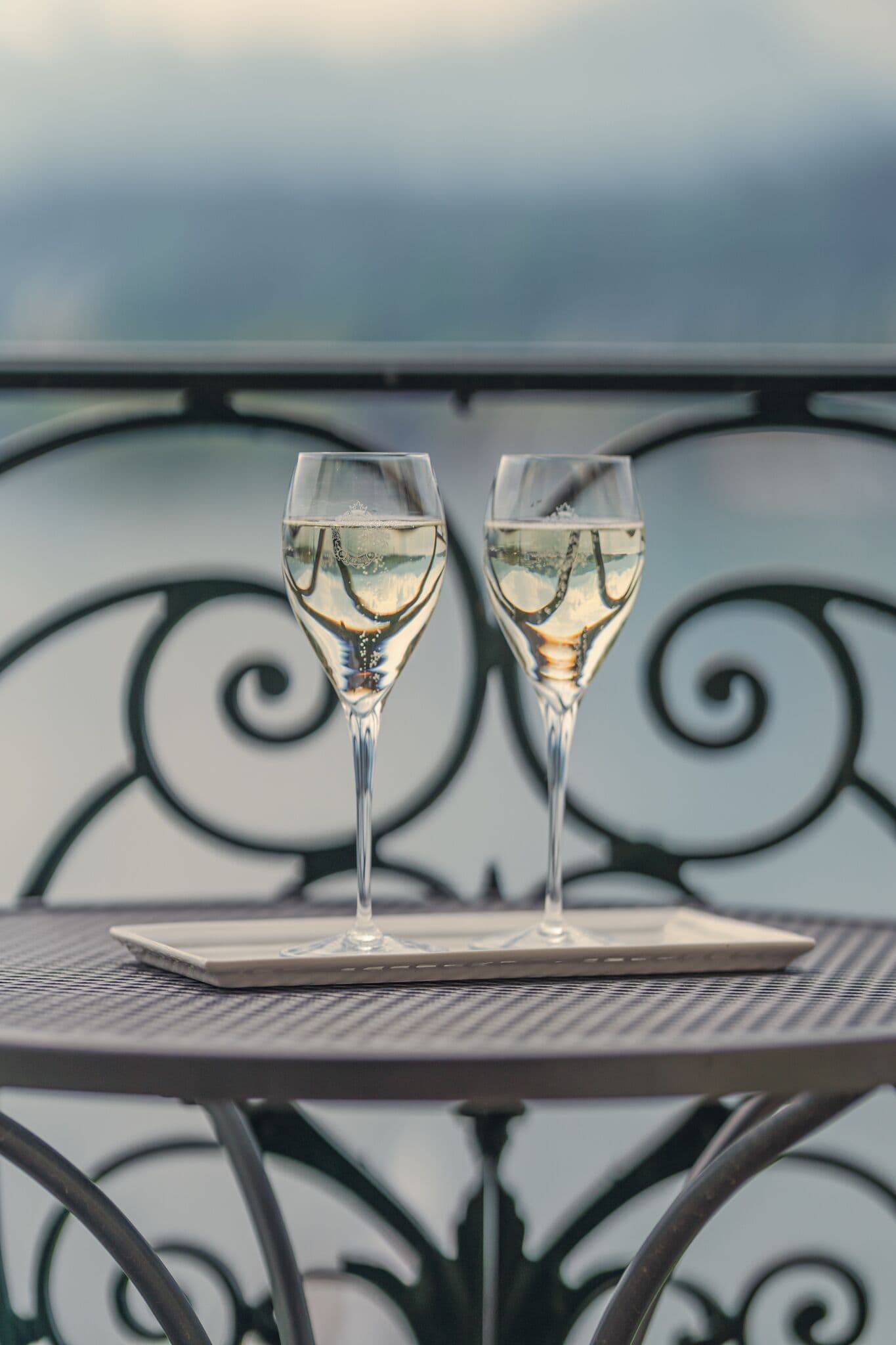 Zwei Gläser Weißwein auf einem Metalltisch mit dekorativem Hintergrund.