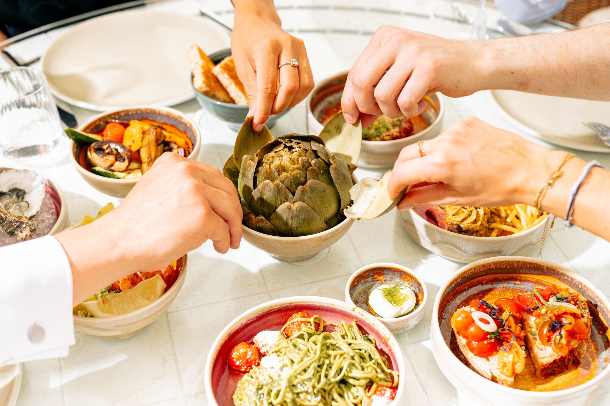 Un grupo de personas comiendo en una mesa con varios platos, incluyendo pasta, mariscos y verduras.