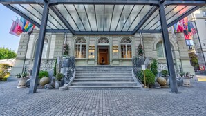 A grand entrance with a covered staircase, arched windows, and a well-maintained garden area. - Grand Hotel National (Lucerne)