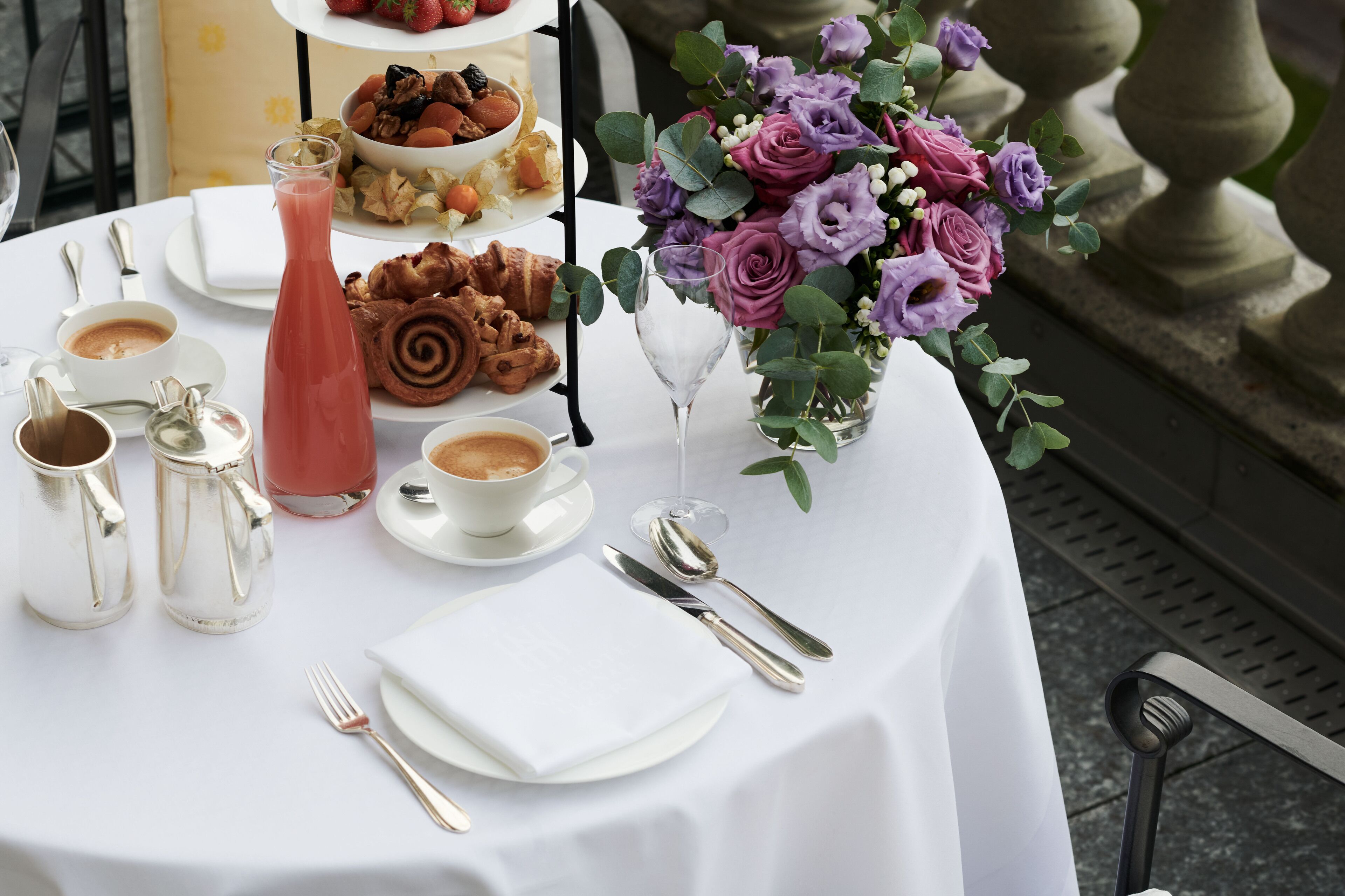 A table set for breakfast with coffee, pastries, and a floral centerpiece.