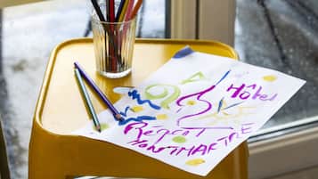 Un taburete amarillo con un vaso que contiene lápices y un pedazo de papel con escritura colorida.