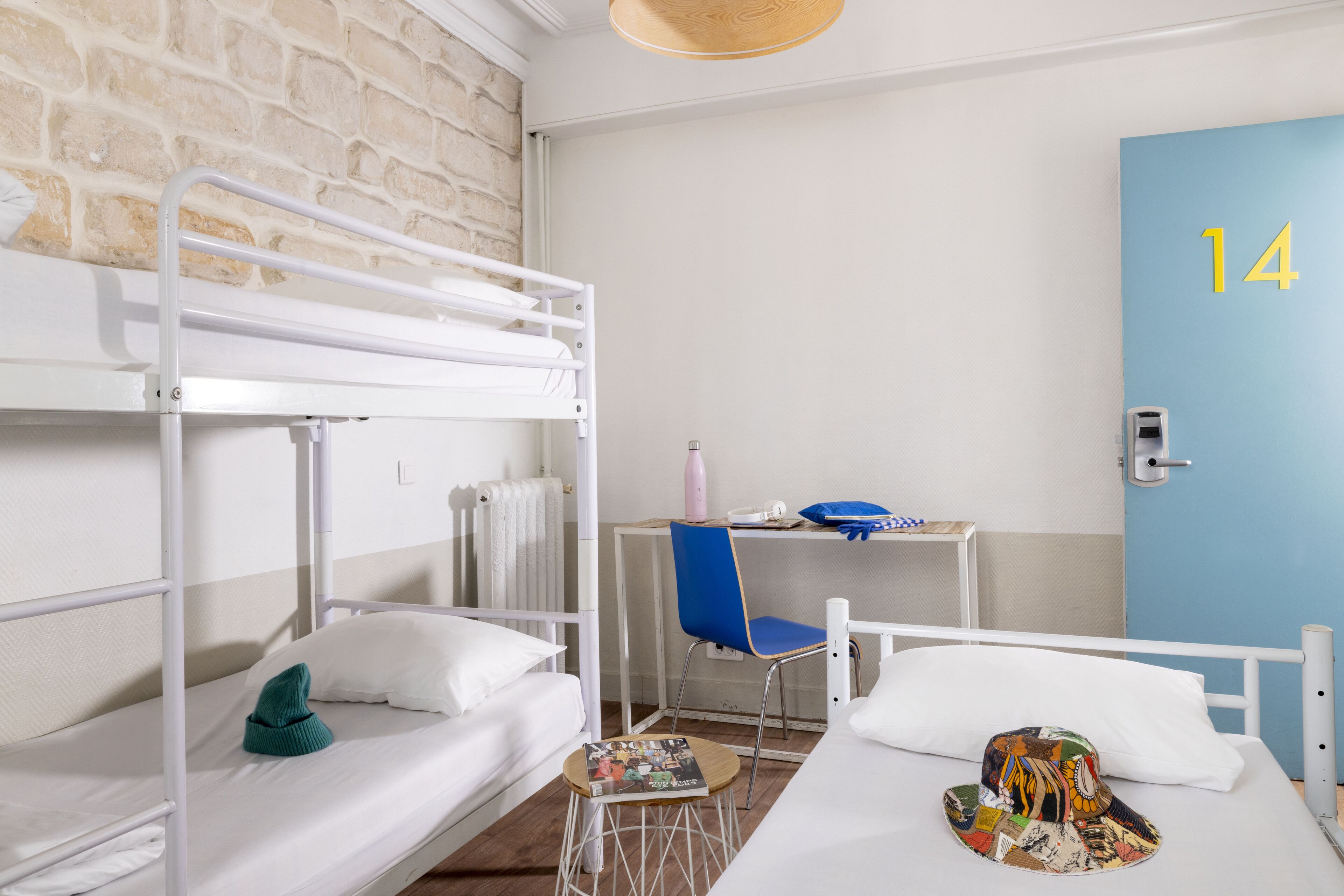 Un dormitorio con literas, un escritorio, una silla y una puerta con el número 14.