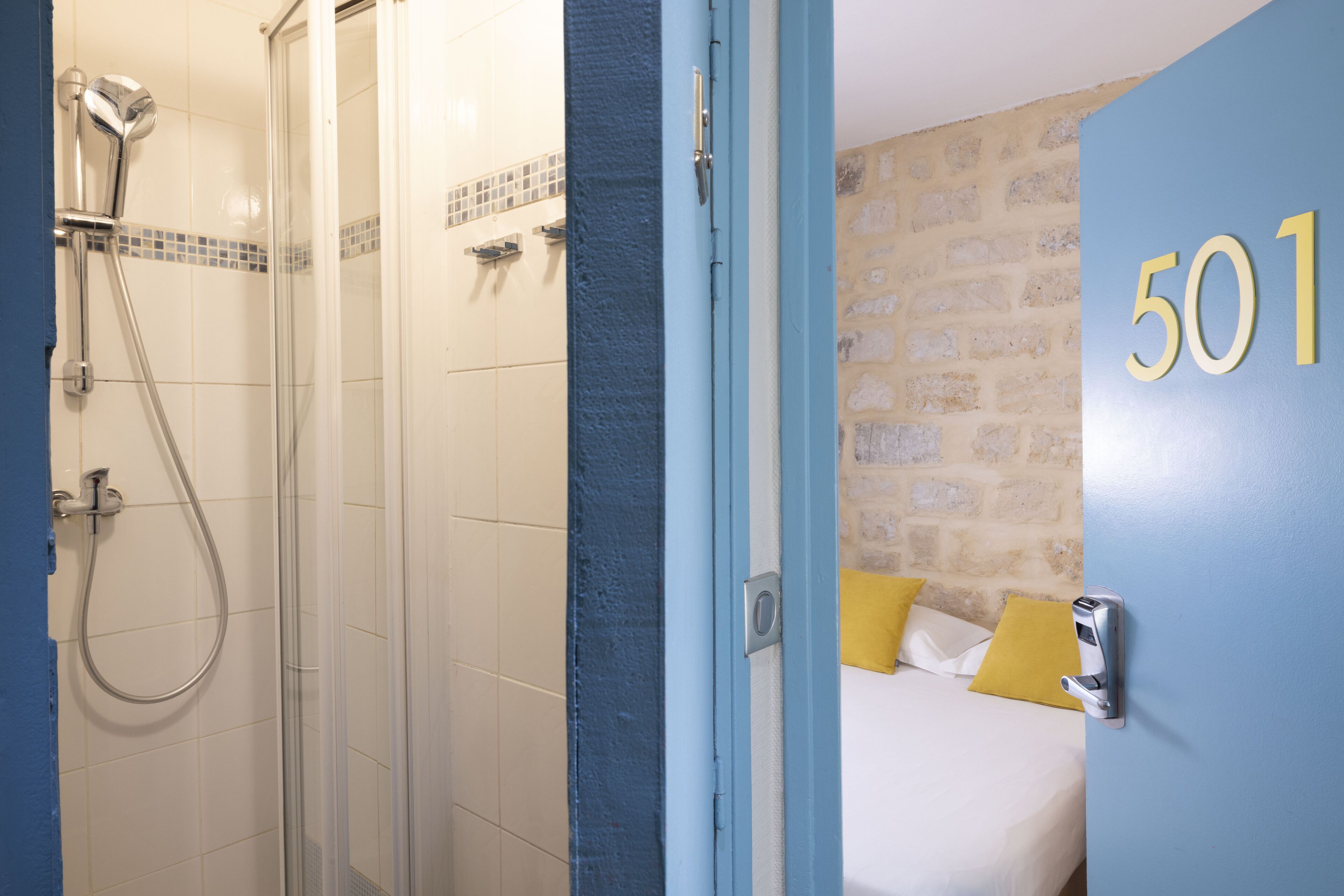 A hotel room with a shower, a bed with yellow pillows, and a wall with the number 501.