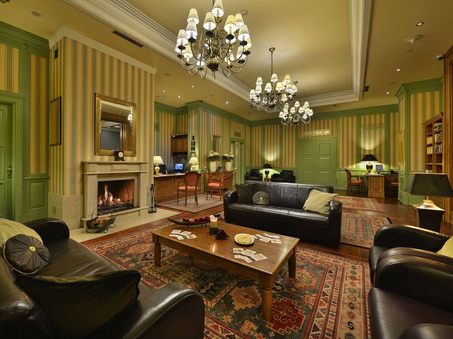 A spacious living room with a fireplace, leather sofas, a coffee table, and a chandelier.