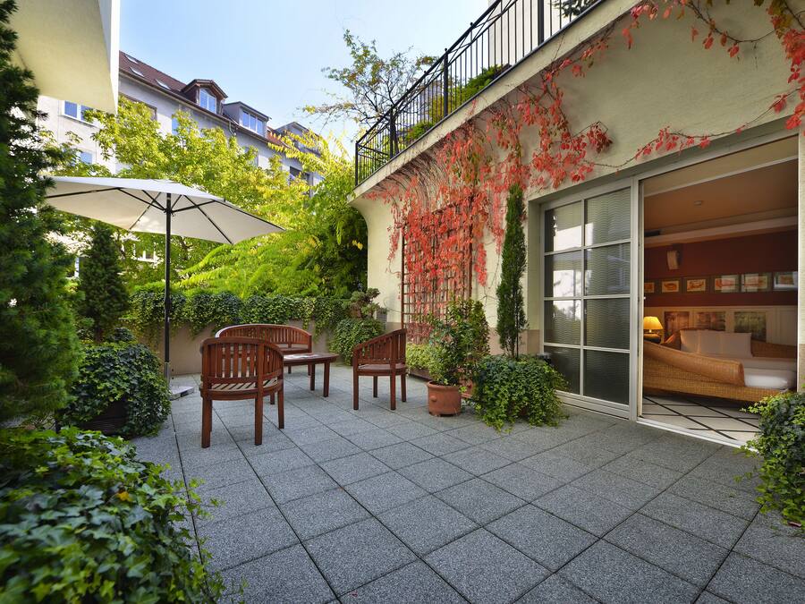 A courtyard with a patio area, outdoor furniture, and a sliding glass door leading to a living space.