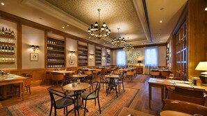Un vestíbul d'hotel amb diverses zones de restauració, mobiliari de fusta i una àmplia col·lecció de vi a les prestatgeries.