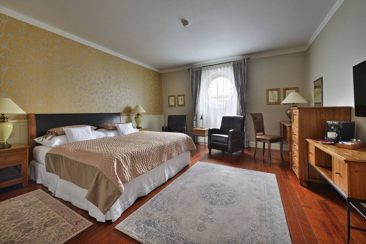 Een hotelkamer met een groot bed, een bureau, een stoel, een dressoir en een televisie.