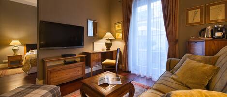 A living room with a television, wooden furniture, a coffee maker, and a window with curtains.