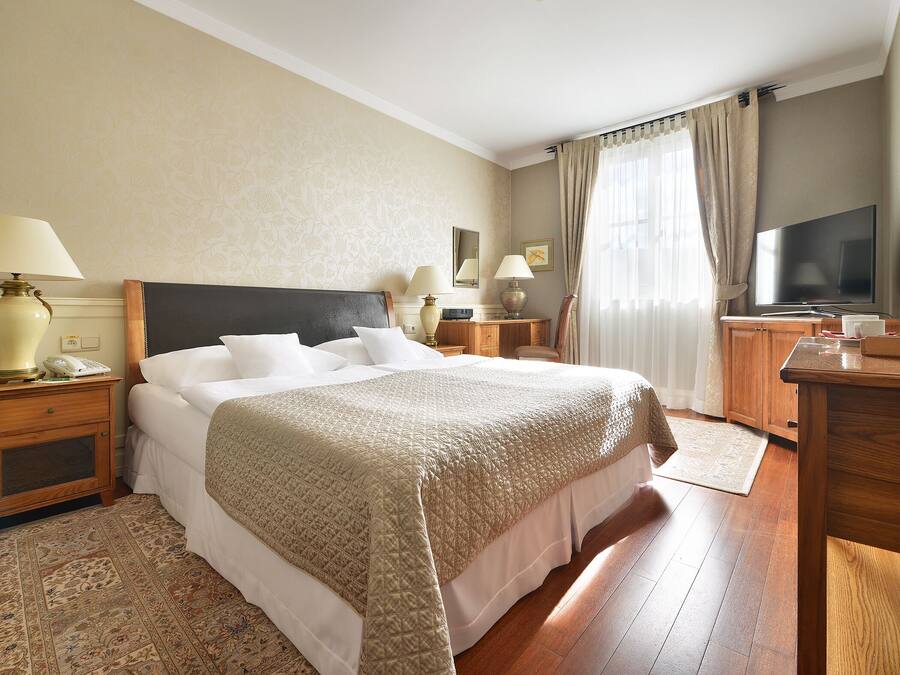 Une chambre d’hôtel avec un grand lit, une télévision, une table de chevet en bois, un bureau et une lampe de bureau.