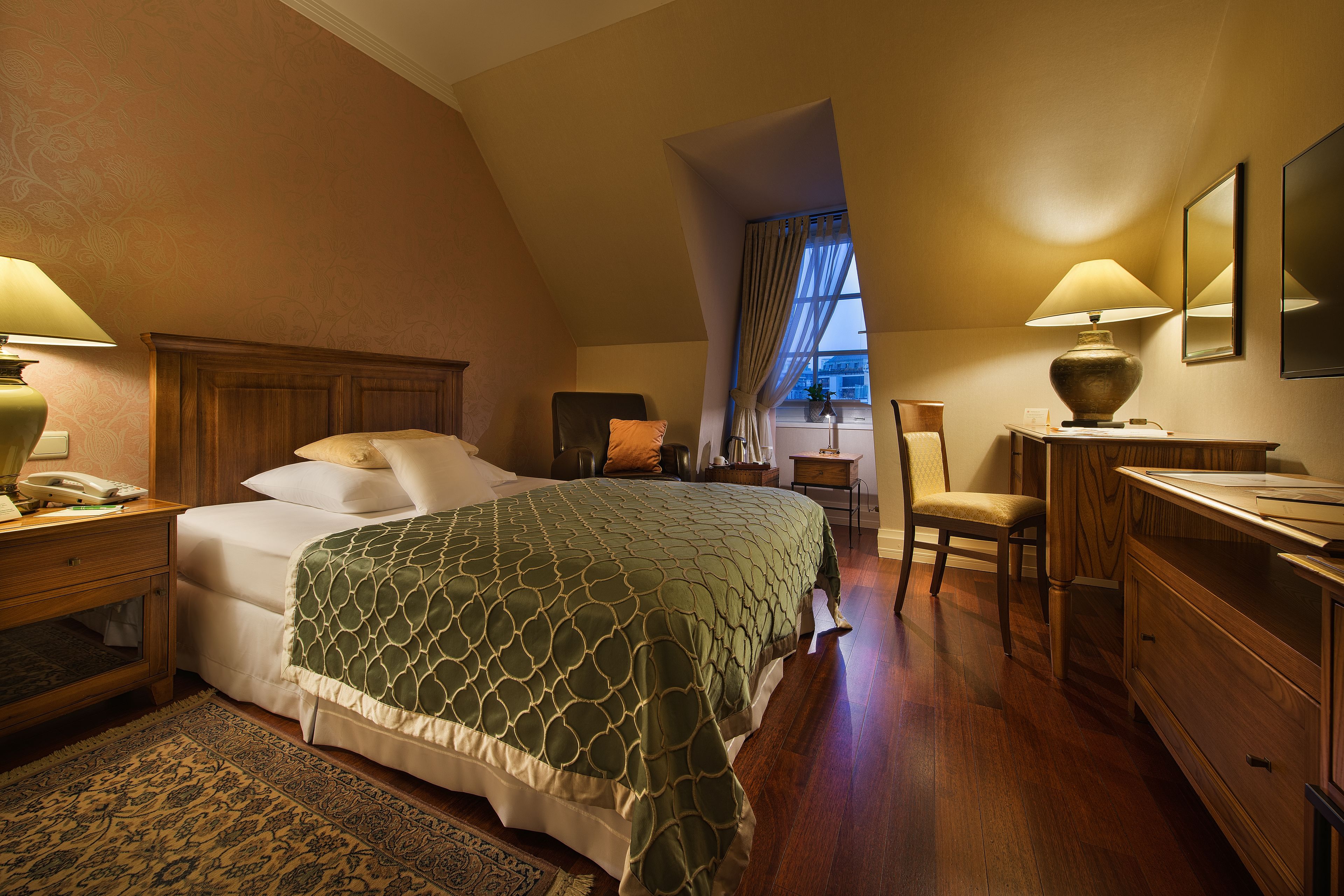 A bedroom with a bed, nightstands, a desk, and a chair.