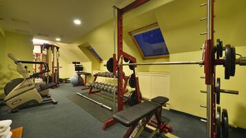 A gym with exercise equipment, a bench, and a mirror.