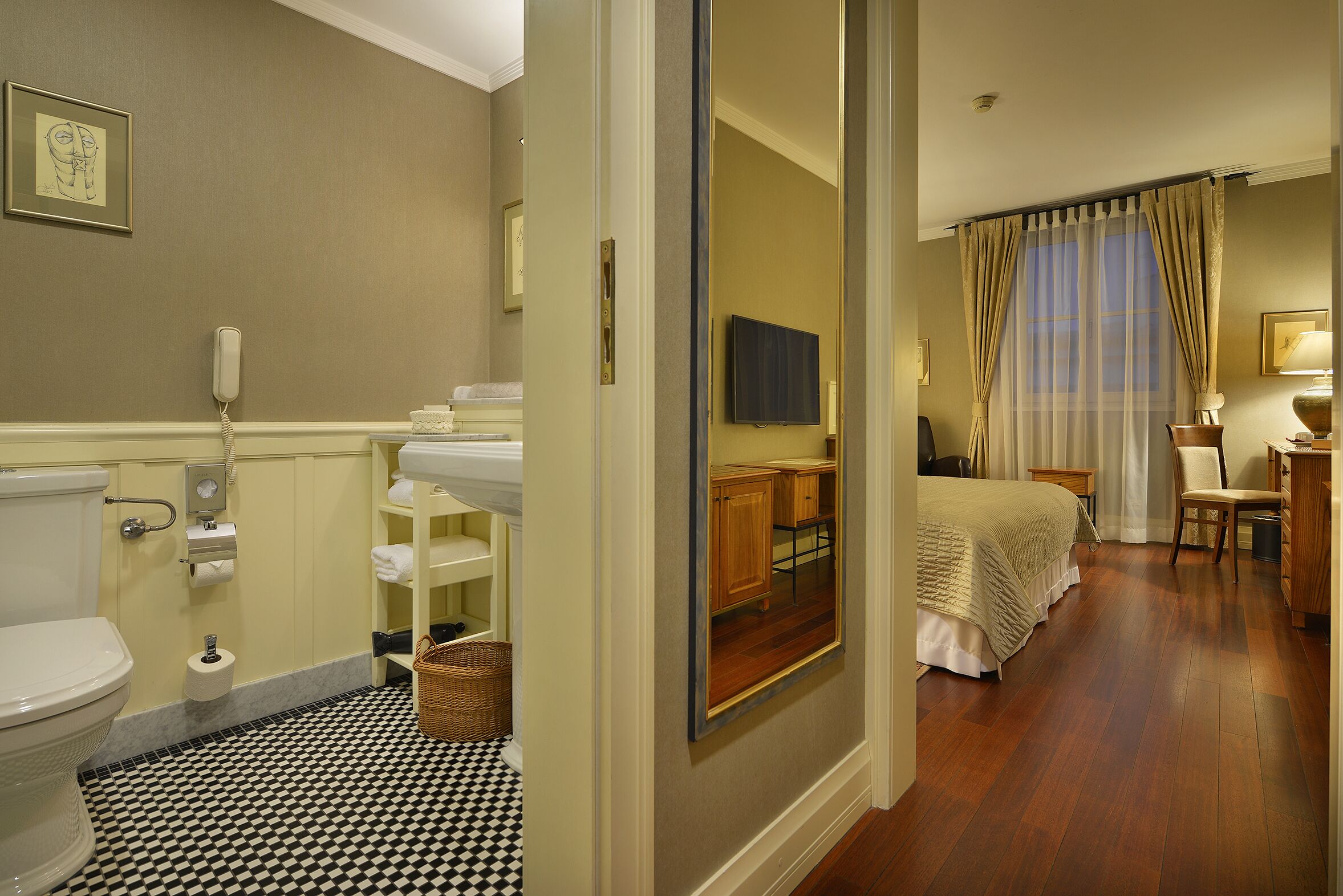 Un baño de hotel con inodoro, lavamanos y espejo.