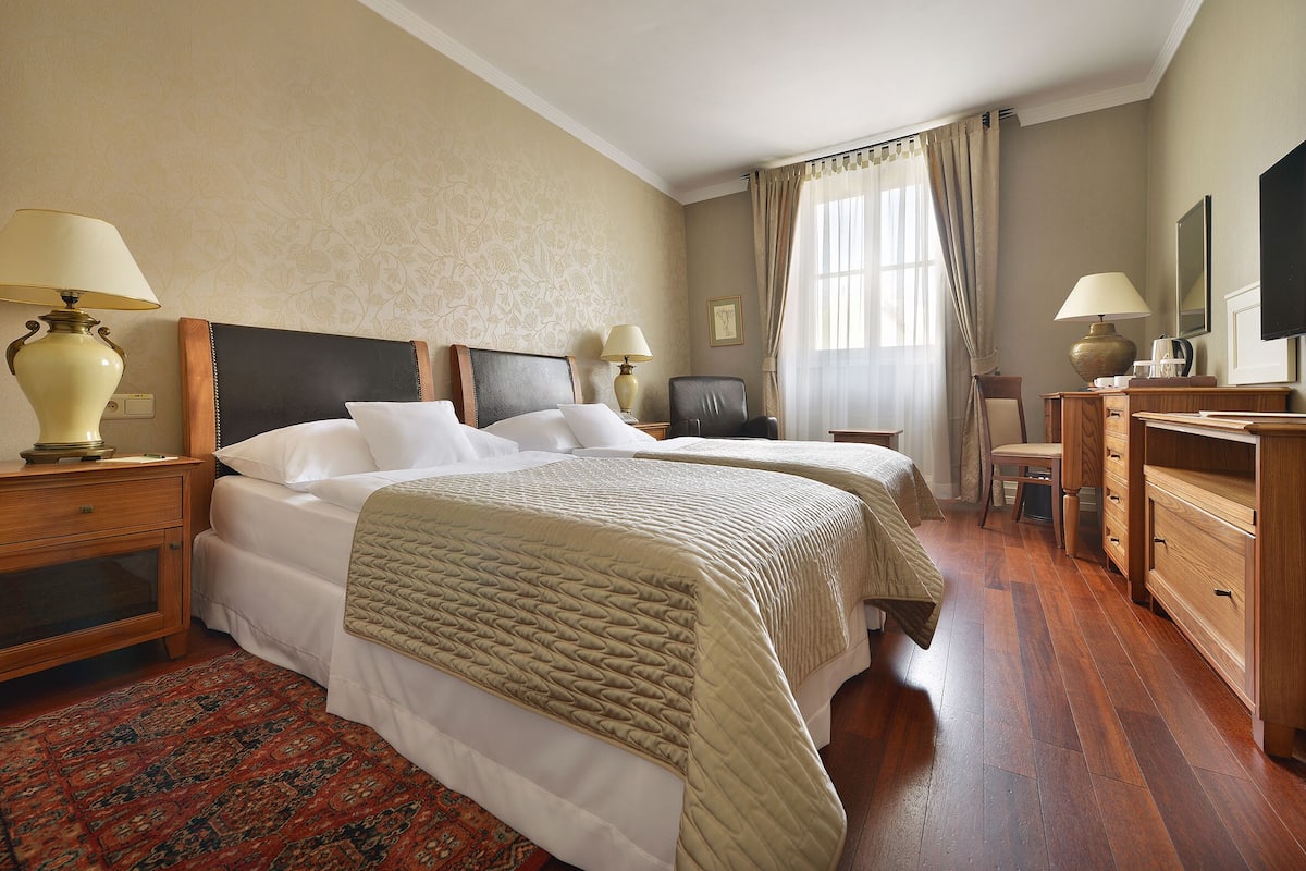 Een hotelkamer met twee bedden, houten meubels, een bureau en een televisie.