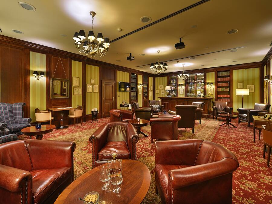 Eine Hotelhalle mit Ledersesseln, einer Bar und einem Teppichboden.