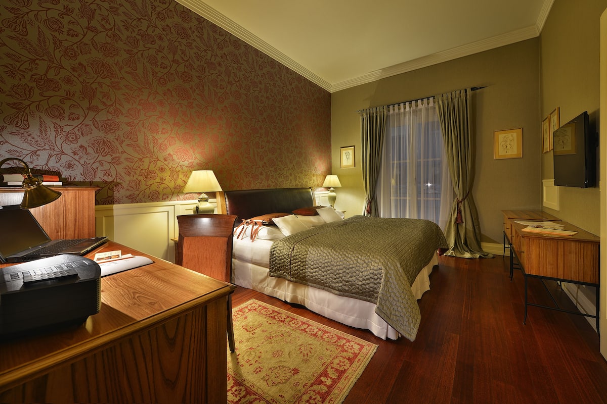 Een hotelkamer met een bed, bureau en een televisie.