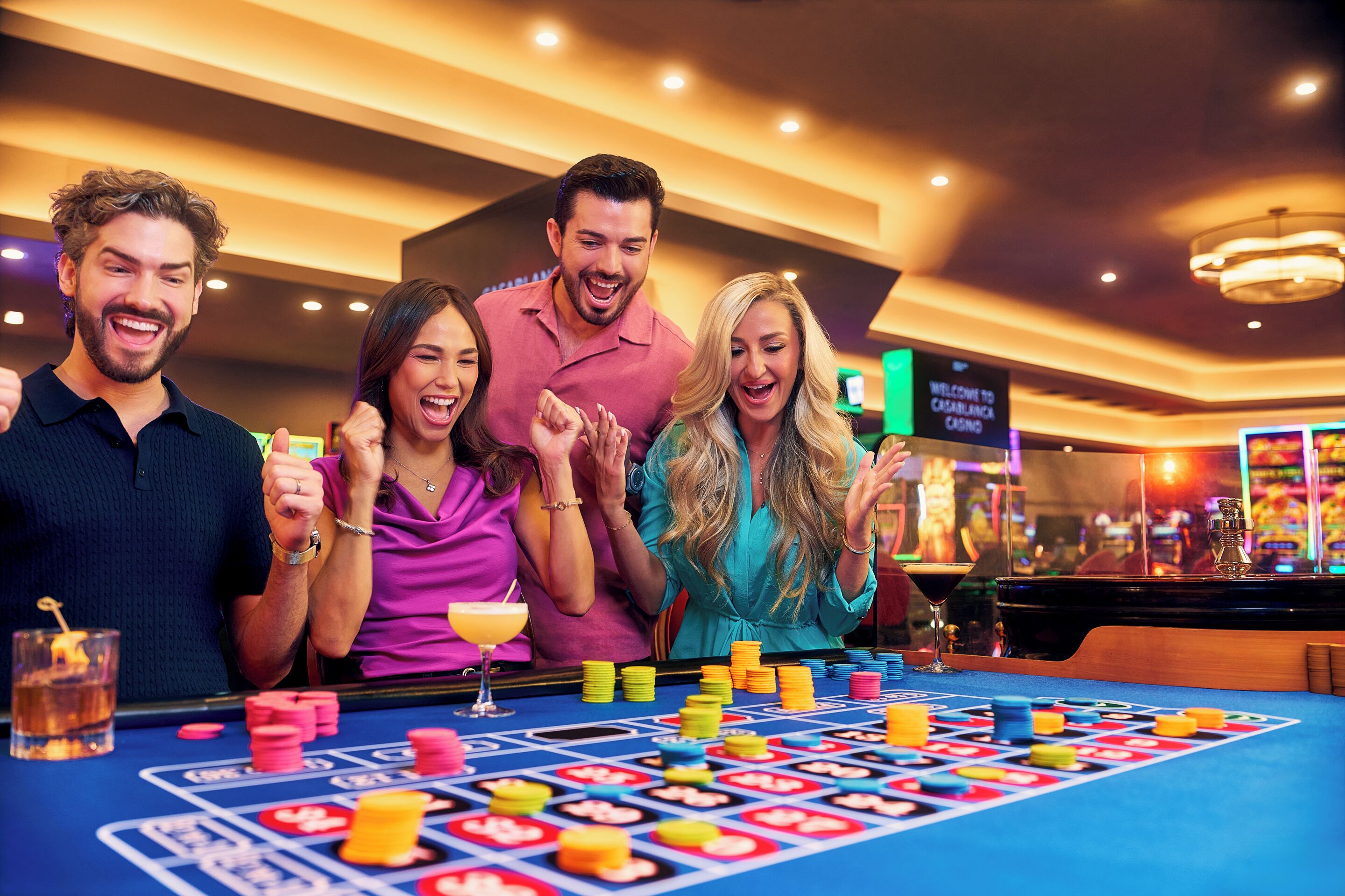 Een groep mensen speelt een spel aan een casino tafel met chips en een roulette wiel.
