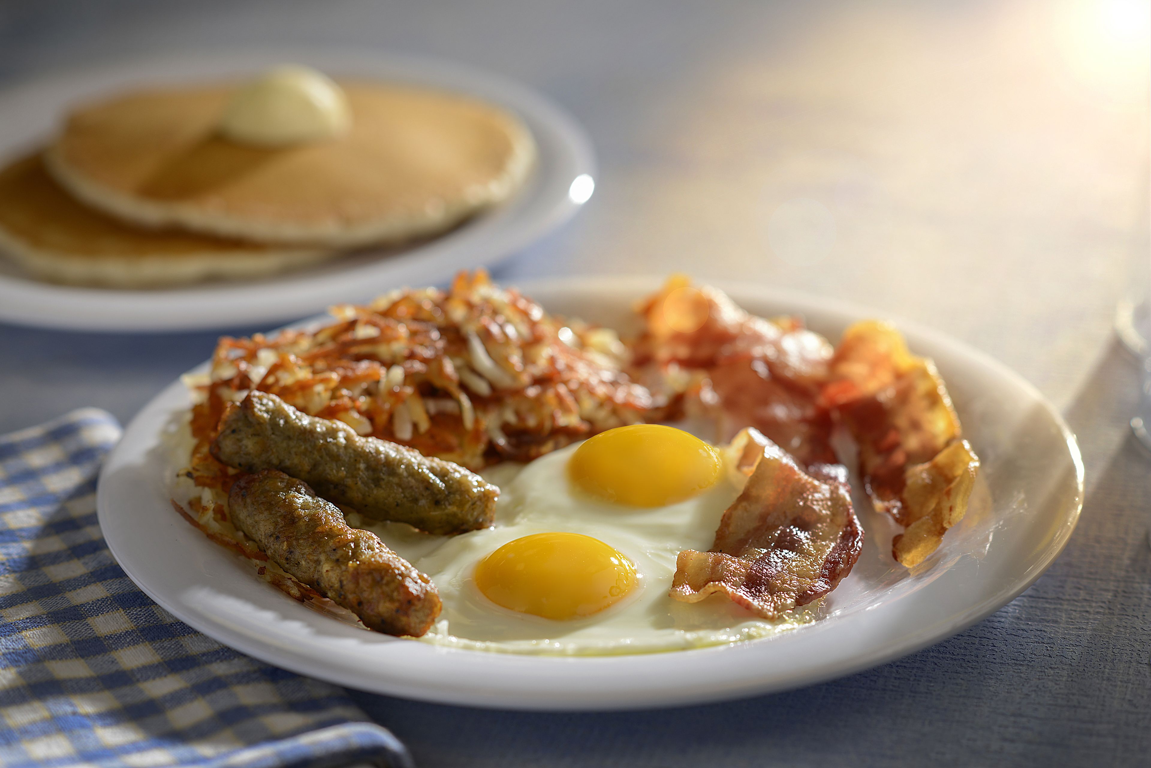 A breakfast plate with eggs, bacon, sausage, and hash browns.