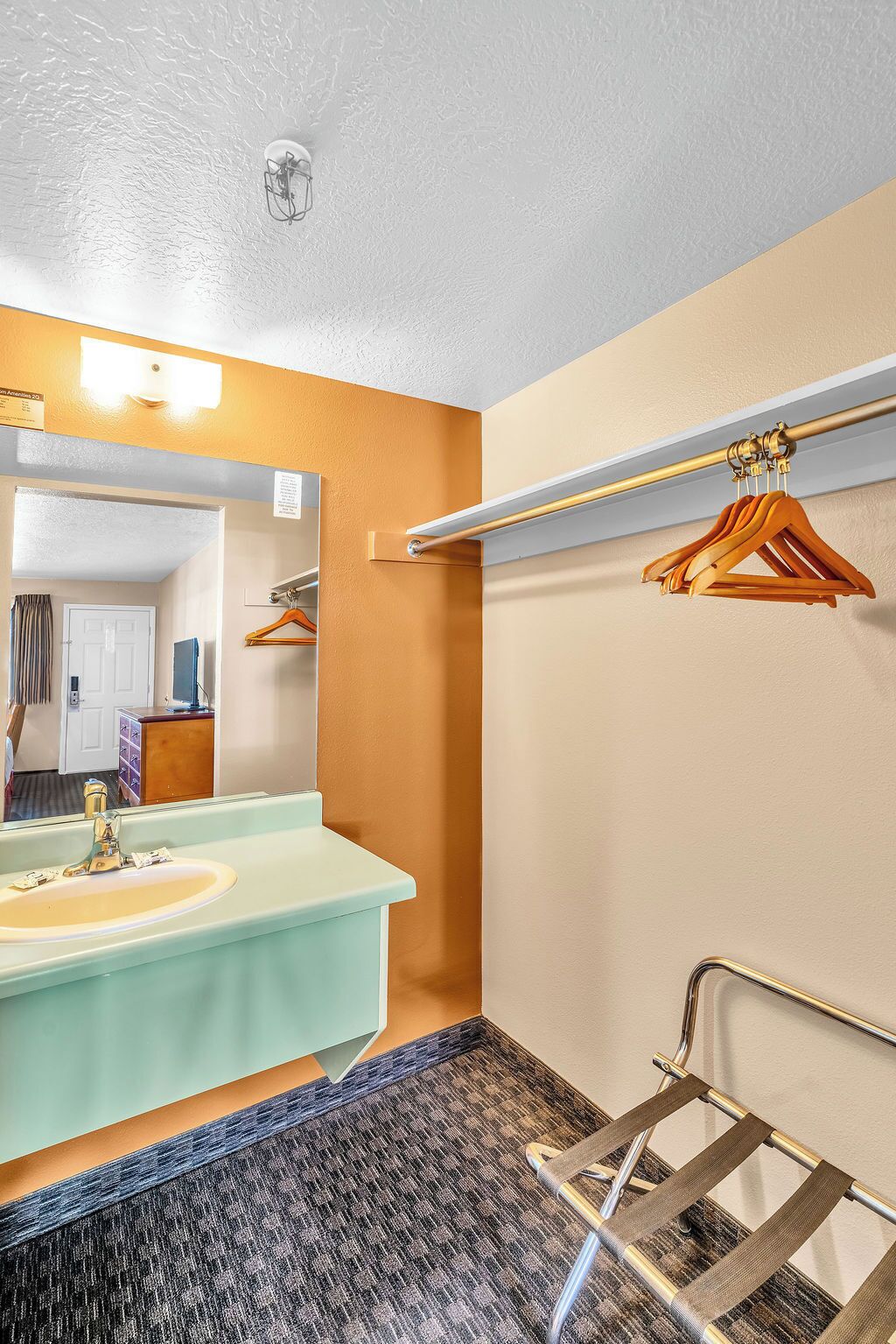 A bathroom with a sink, mirror, towel rack, and a shower area.