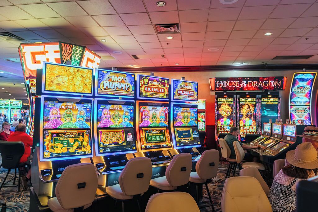 Un salón de casino con múltiples máquinas tragamonedas, incluyendo los juegos 'MO' y 'House of the Dragon'.