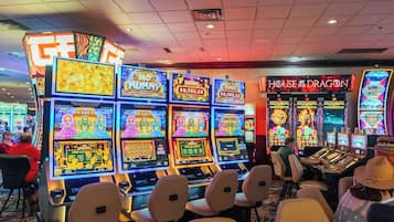 Un salón de casino con múltiples máquinas tragamonedas, incluyendo los juegos 'MO' y 'House of the Dragon'.