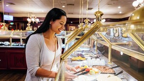 Un espace buffet proposant une variété de plats et une personne qui sert les clients.