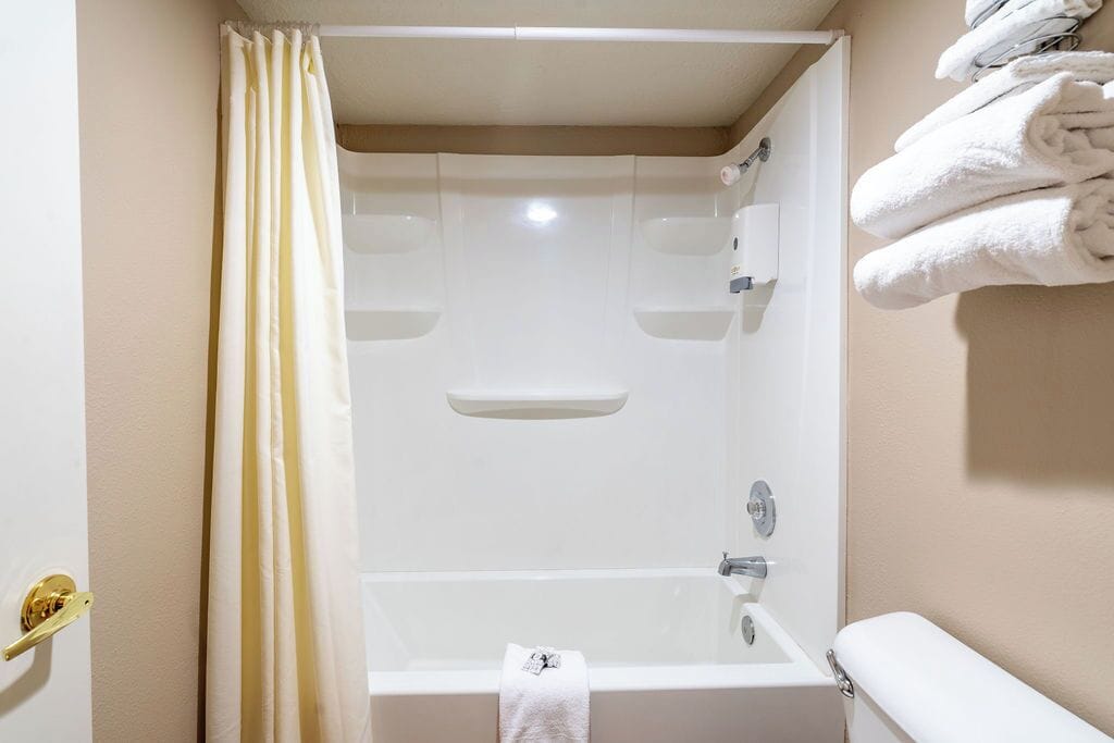 A bathroom with a bathtub, a towel rack with towels, and a toilet.