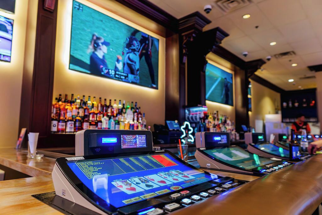Eine Bar mit Spielautomaten und einem großen Bildschirm, der ein Sportereignis zeigt.