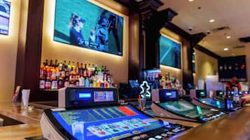 Eine Bar mit Spielautomaten und einem großen Bildschirm, der ein Sportereignis zeigt.