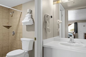 A modern bathroom with a toilet, shower, and sink.