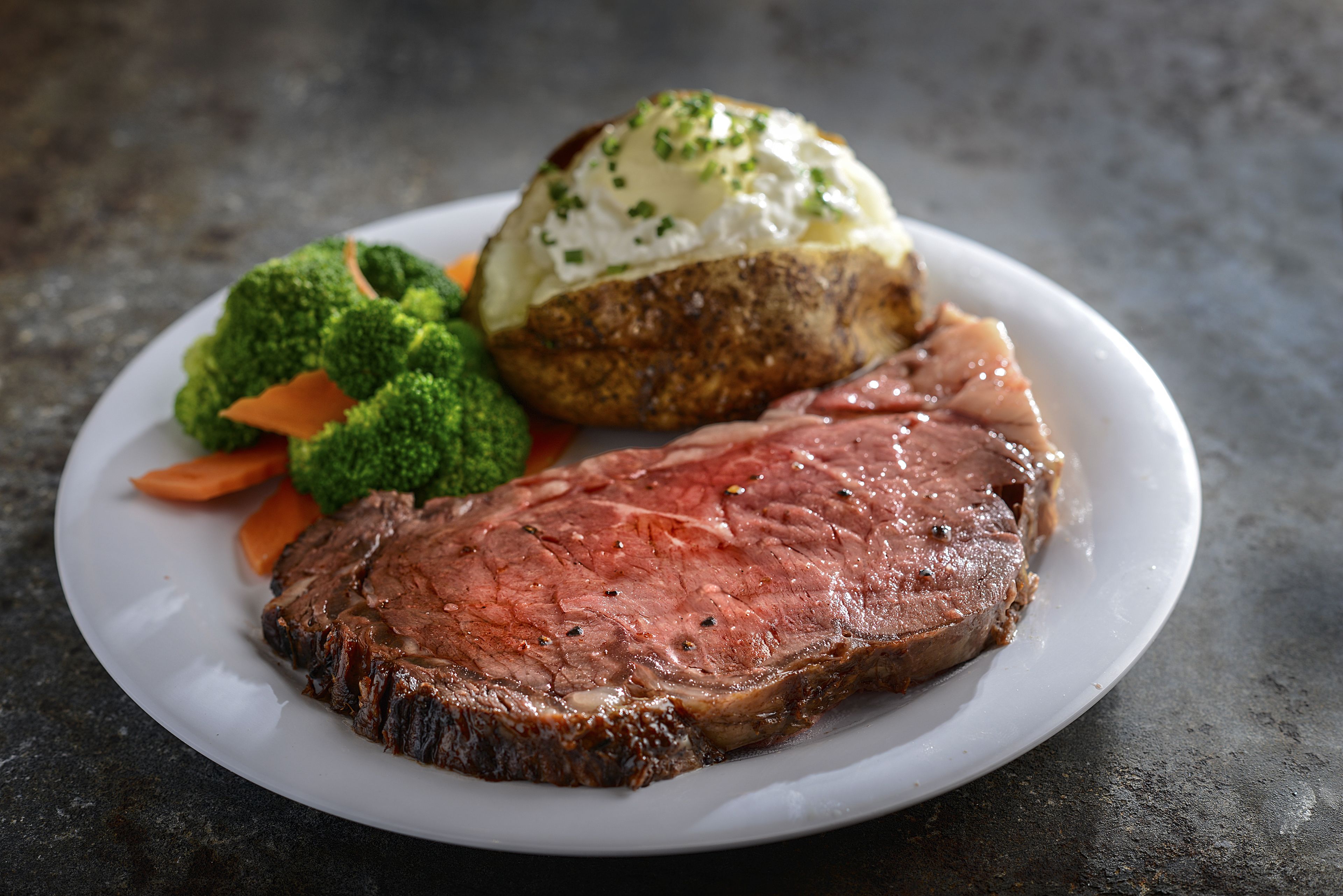A plate with a steak, a baked potato, and steamed vegetables.
