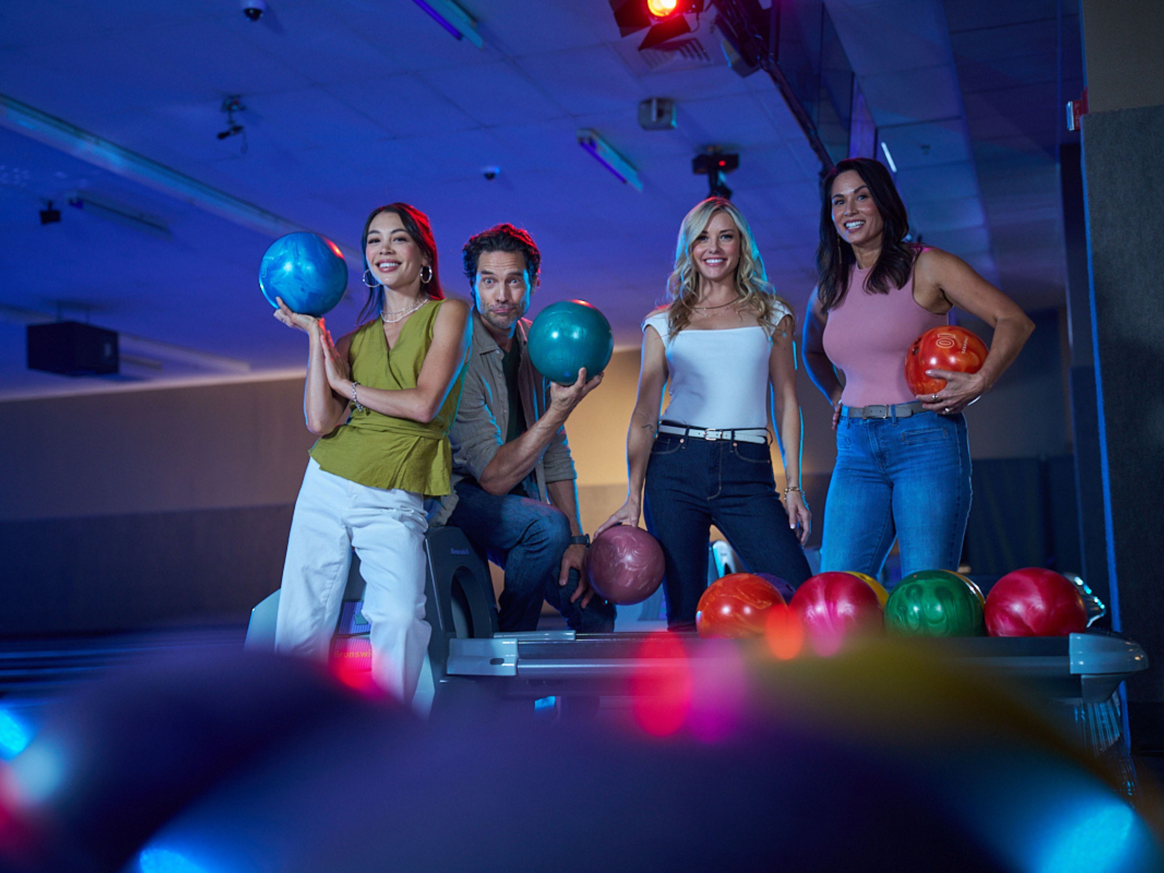 A group of people bowling in a brightly lit indoor facility with a modern design.