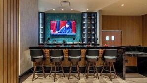 Eine moderne Bar mit Fernseher, Barhocker und einer Minibar.