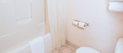 A bathroom with a bathtub, toilet, and a shower curtain.