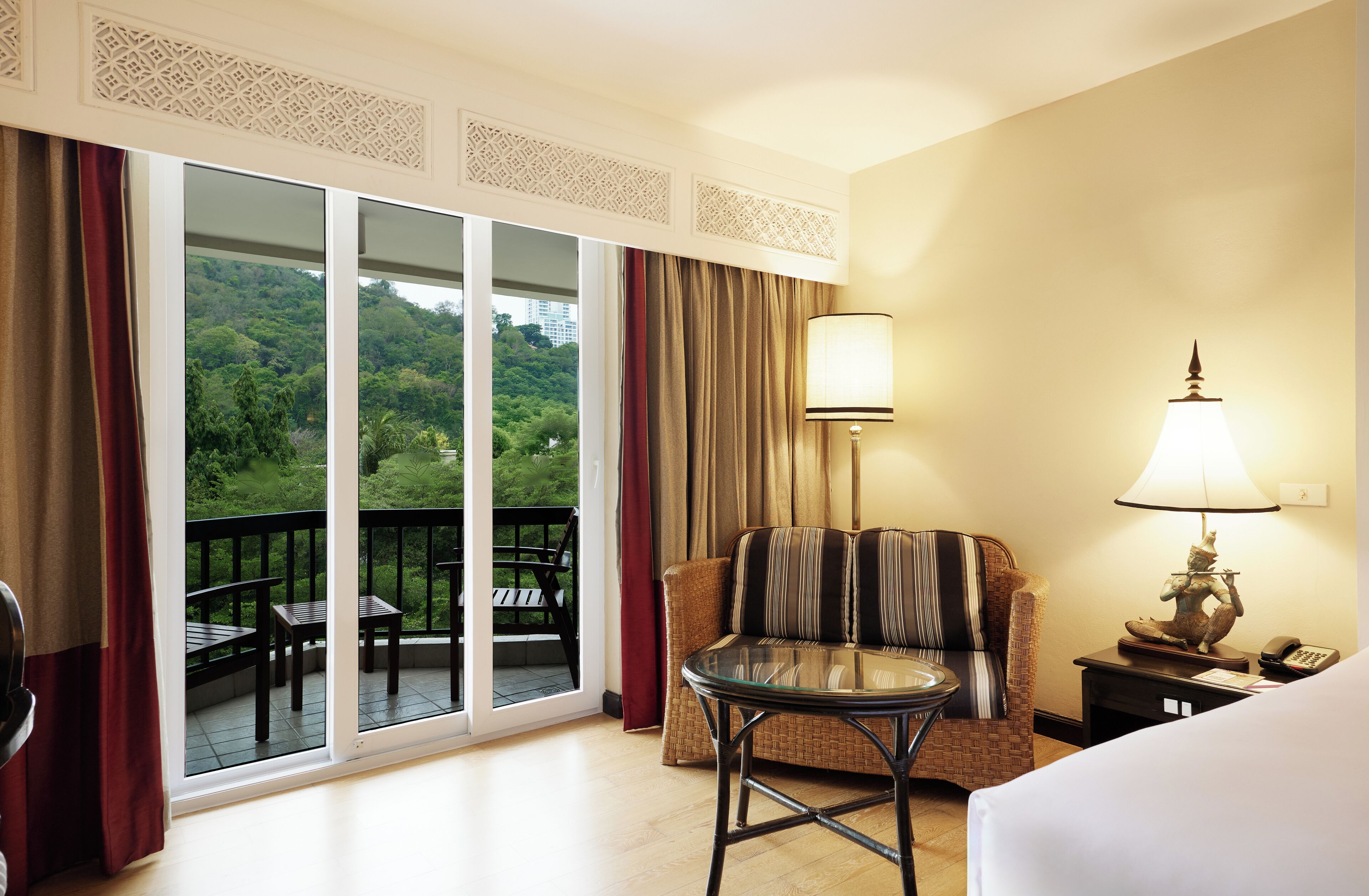 Quarto de hotel com varanda, sofá, mesa e luminária.
