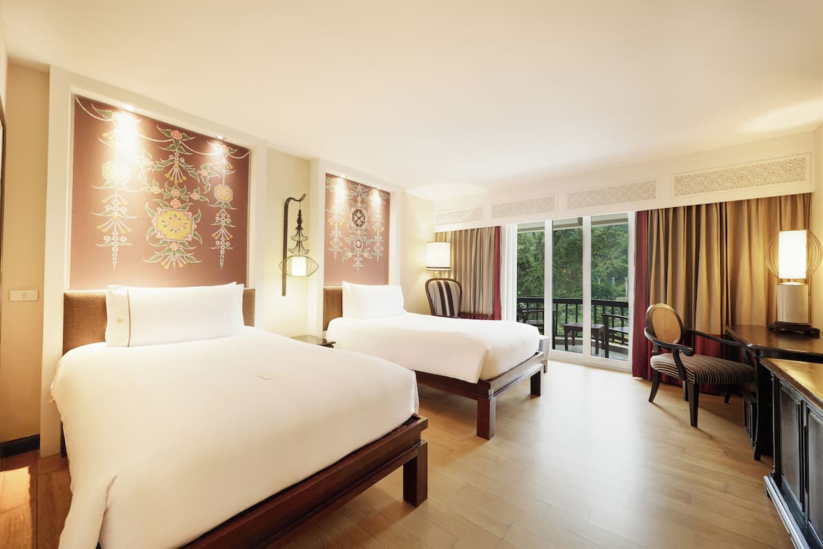 A hotel room with two beds, a desk, and a chair.
