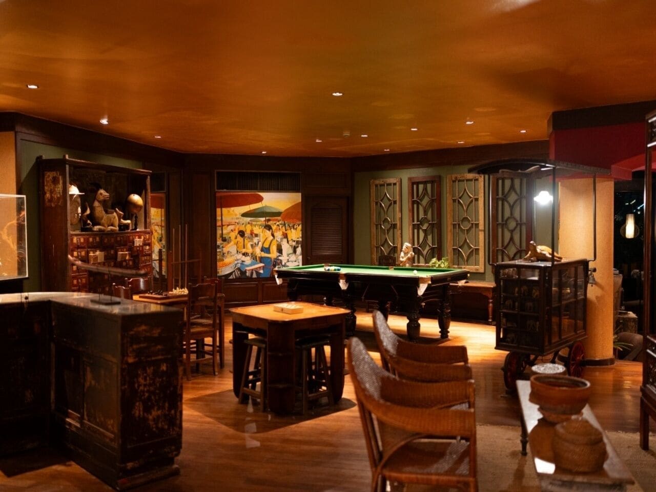 A billiards room with a pool table, wooden furniture, and decorative items.
