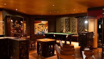 A billiards room with a pool table, wooden furniture, and decorative items.