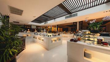 A spacious hotel lobby with multiple seating areas, a reception desk, and a buffet setup.
