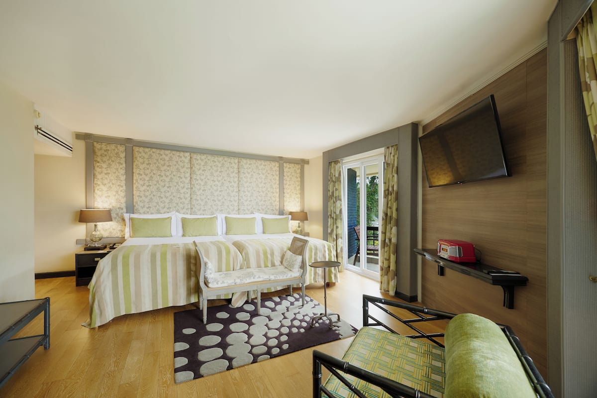 A bedroom with a bed, bedside tables, a TV, and a window with curtains.