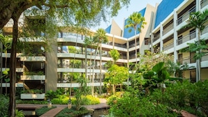 Ein mehrstöckiges Hotel mit Innenhof, der ein kleines Wasserelement und üppiges Grün umfasst.