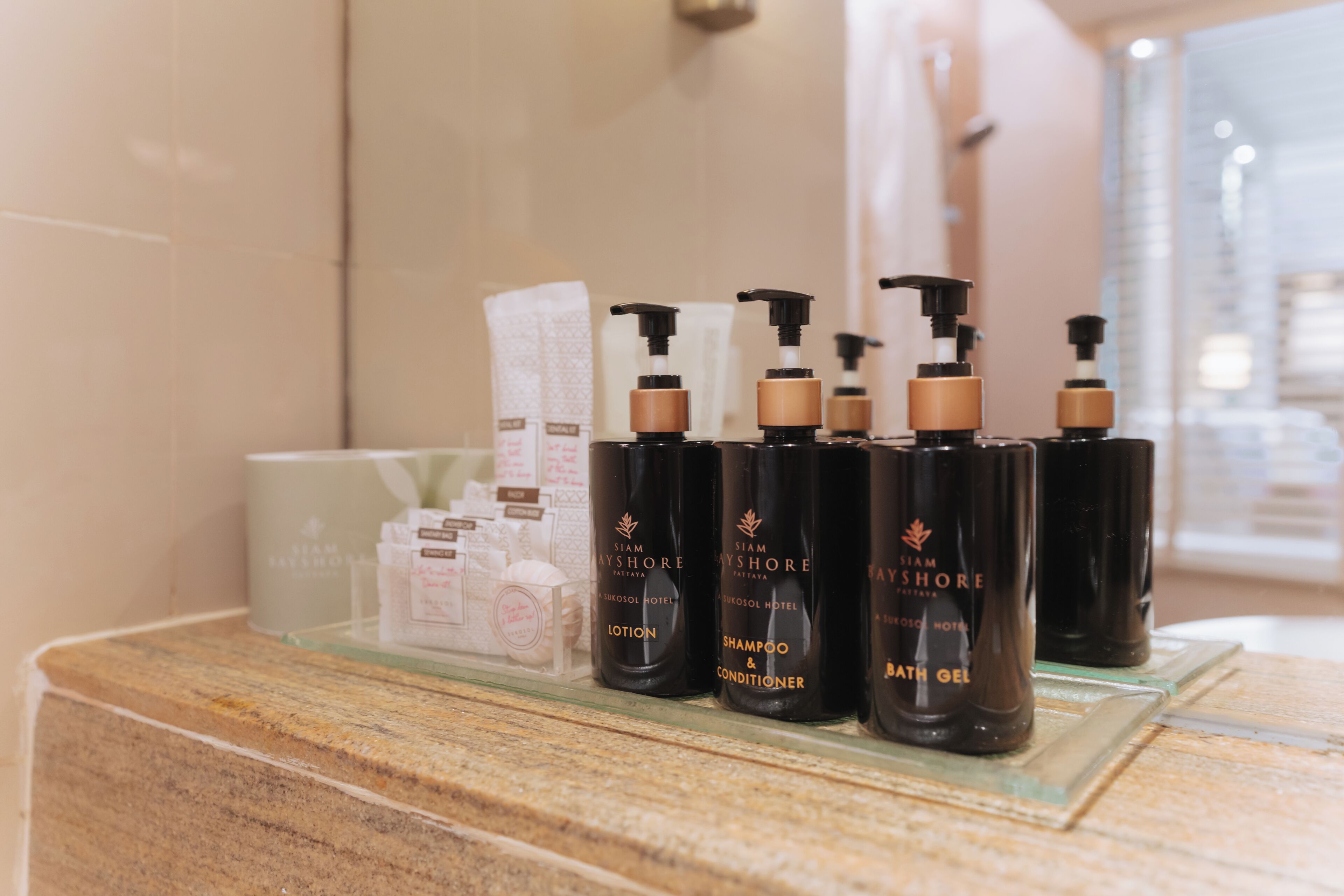 A bathroom counter with toiletries including lotion, shampoo, conditioner, and bath gel.