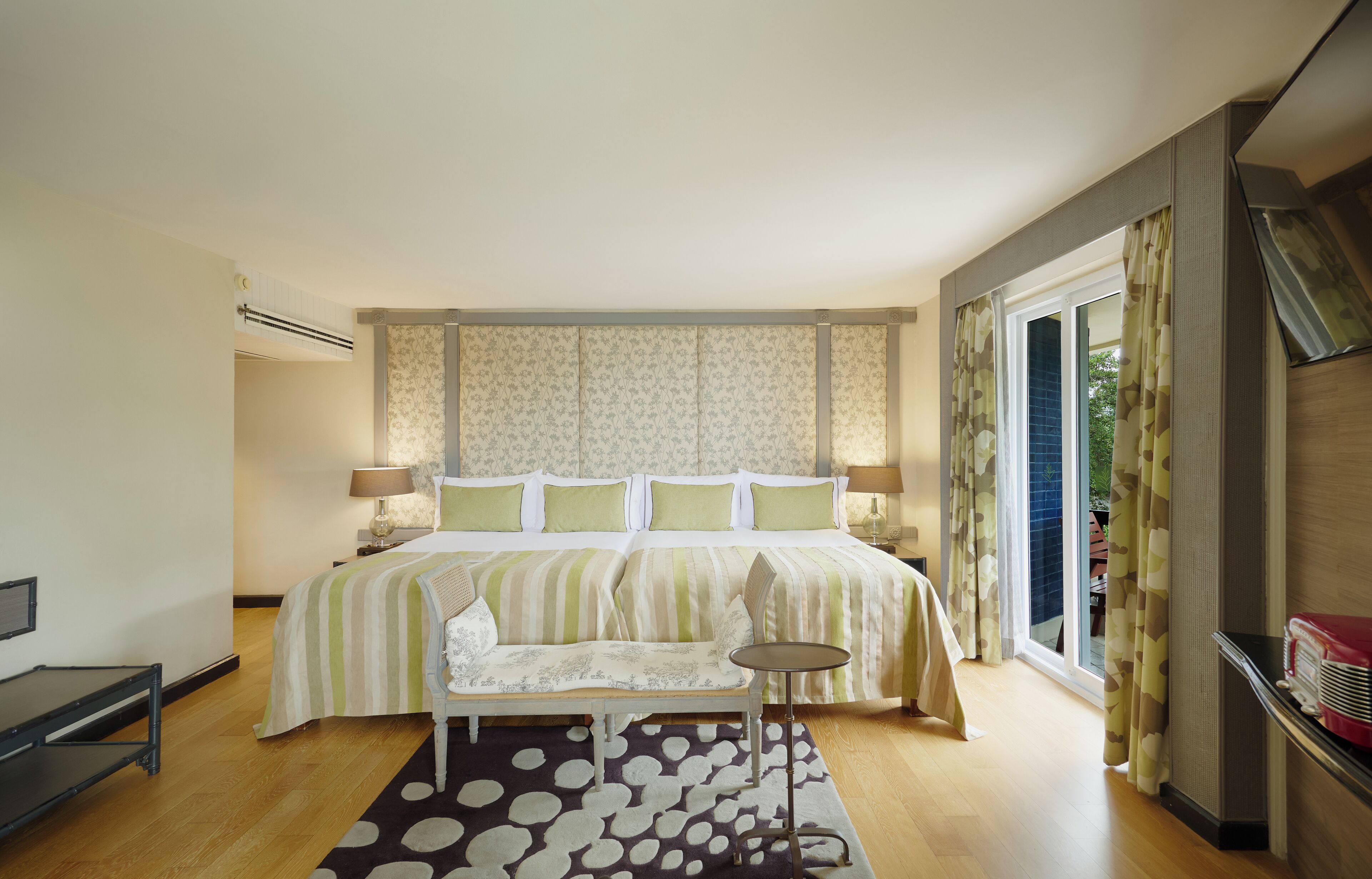 A bedroom with a large bed, bedside tables, a chair, a small table, and a window with curtains.