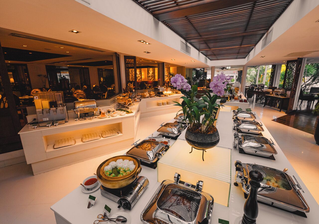 Montaje de bufé con distintas estaciones de comida y un arreglo floral central.